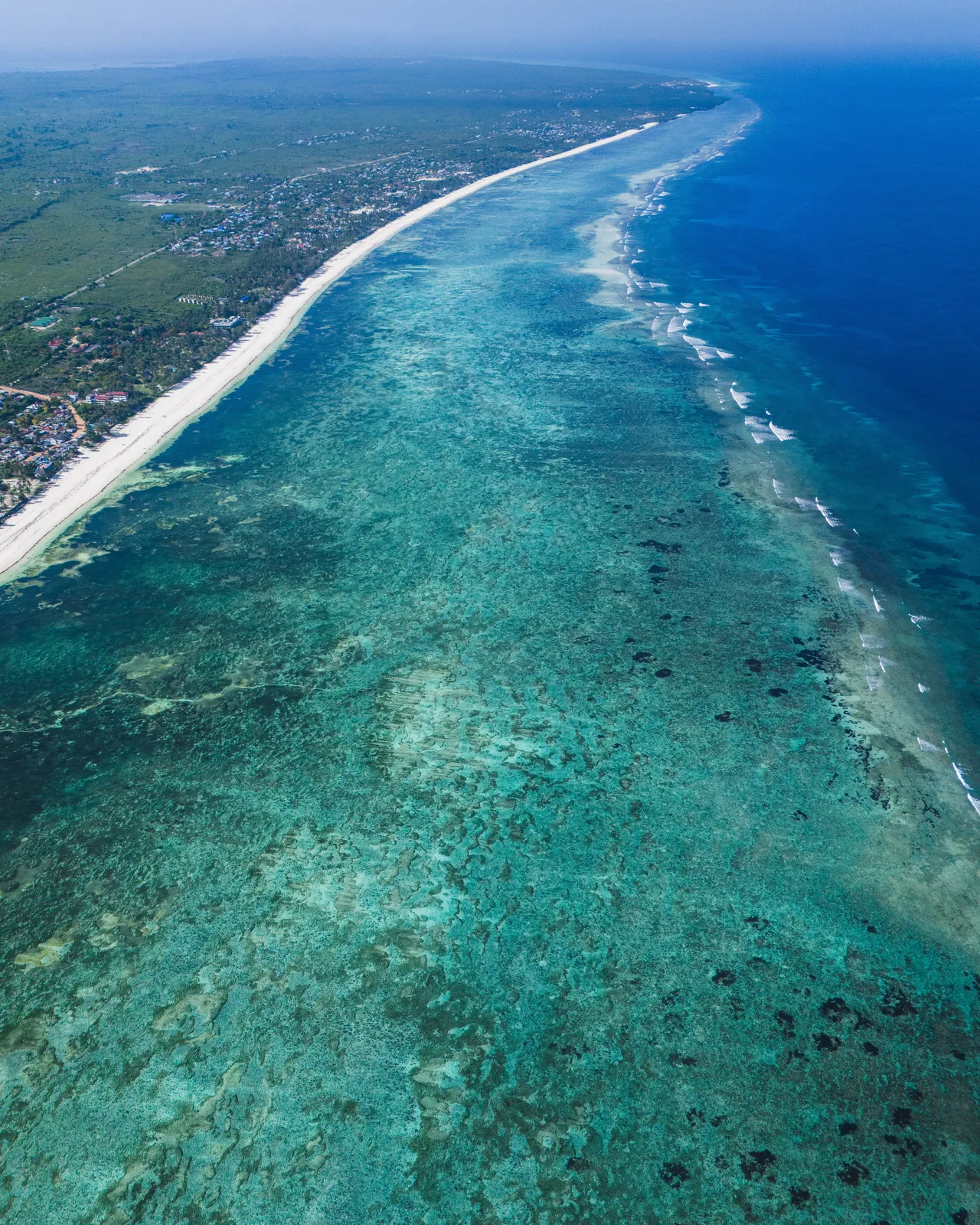 Aerial views reveal crystal-clear turquoise waters, coral reefs, and a beautiful coastline stretching along Kenya’s tropical shores.