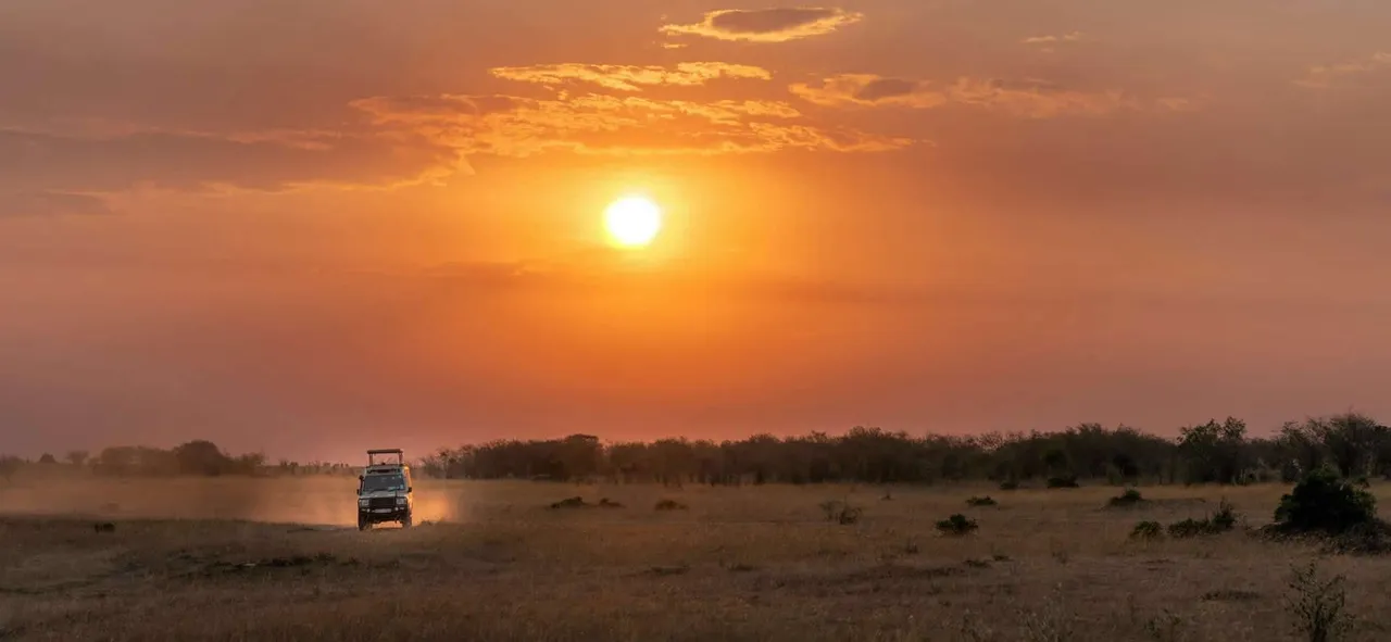 Un vehículo de safari en las llanuras de Kenia al atardecer